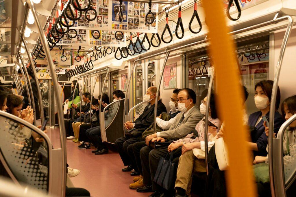 Masked commuters sitting in a Tokyo subway train showcasing urban travel and safety.