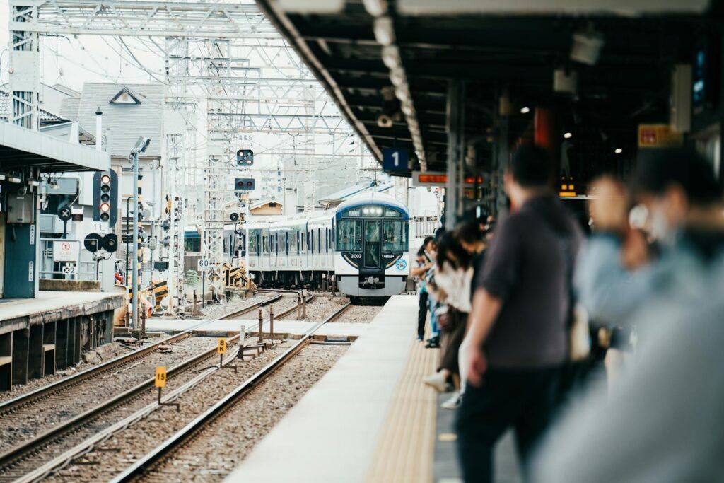 A train arriving at a bustling Japanese station filled with waiting passengers.